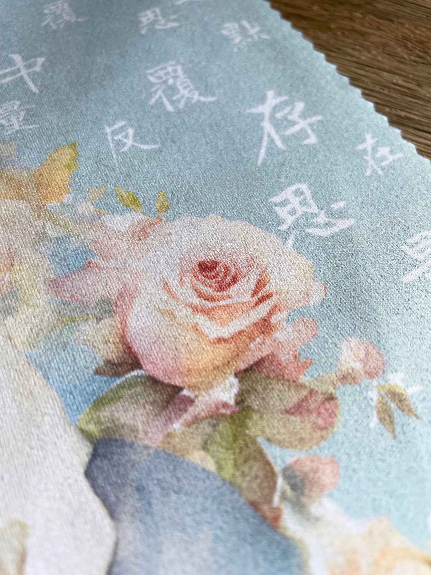 特寫粉藍色眼鏡布上的水彩玫瑰花和聖母瑪利亞的「默存在心中,反覆思量」文字。